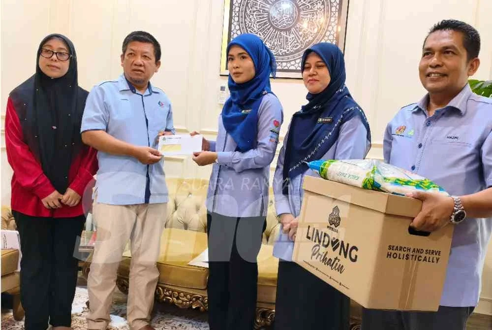 Sharulanuar dan isteri menerima sumbangan Faedah Pengurusan Mayat dan Faedah Orang Tanggungan yang disampaikan oleh Nor Aziemah (tiga dari kanan) di rumah mereka di lorong kubur Taman Mekasar, Kasar, Pasir Mas pada Isnin.