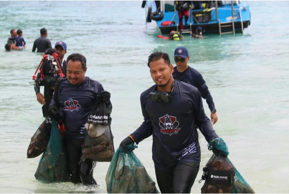 Penyelam sukarelawan membawa naik sisa marin yang dikutip dari dasar laut.