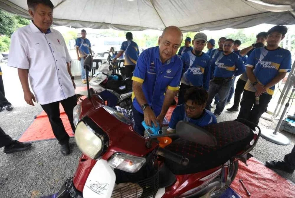 Zaliman (tengah) mengisi minyak enjin motosikal sambil berkongsi kepentingan kemahiran TVET kepada peserta Program Mechanics on Wheel di SMK Ayer Lanas, Jeli pada Isnin. - FOTO: UniMAP
FOTO UniMAP