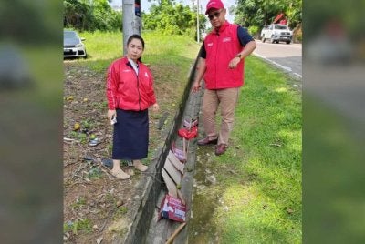 Chu Poh Yee (kiri) menunjukkan bahan kempen yang dirosakkan. - Foto FB Chu Poh Yee