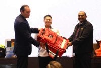 James (kiri) melakukan gimik penyerahan sumbangan peralatan perubatan kepada Dr Muthu Chelvan.
