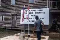 Seorang lelaki berdiri tepat di atas penanda sempadan Indonesia-Malaysia di Pulau Sebatik, bersebelahan sebuah rumah yang ruang tamunya terletak di Indonesia, manakala bilik keluarga dan dapurnya berada dalam wilayah Malaysia. Foto Agensi