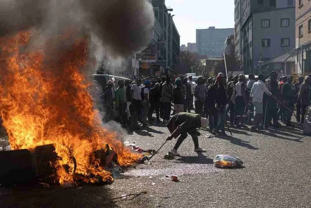 Penunjuk perasaan berhimpun di luar sebuah bangunan yang dipercayai didiami warga asing tanpa dokumen sah ketika demonstrasi di Johannesburg. -Foto AFP.