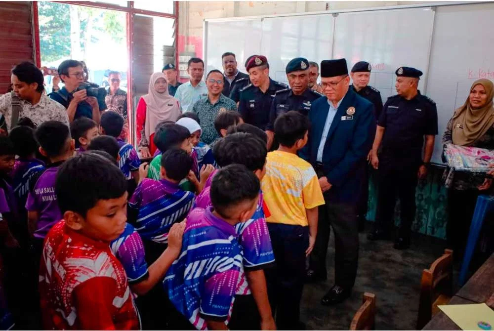 Fadil (dua dari kanan) beramah mesra dengan para murid sekolah di sini pada Khamis.