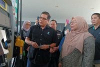 Fuziah (kanan) melihat proses pengisian bantuan subsidi Budi Madani Diesel di Stesen Minyak Petronas Bandar Dato Onn pada Khamis.