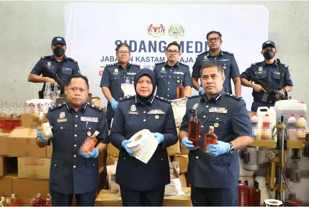 Noraidah (tengah) menunjukkan antara rampasan barang kes hasil tindakan ke atas sindiket memproses minuman keras dan penyeludupan produk tembakau. Foto: JKDM KUALA LUMPUR