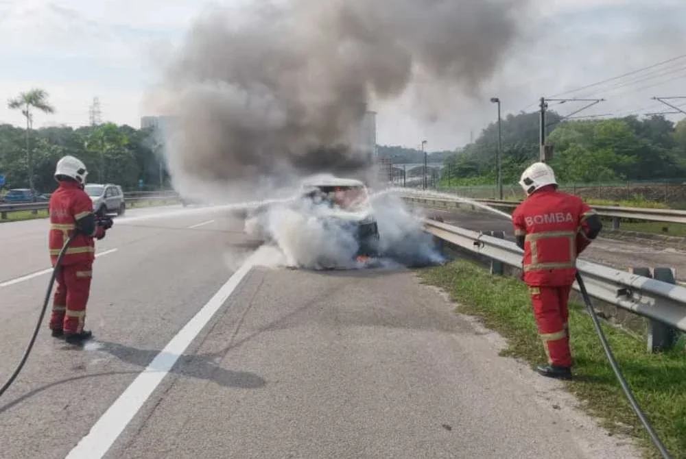 Anggota bomba sedang memadamkan kebakaran sebuah MPV di sini pada Jumaat.