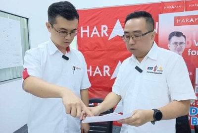 Lih Kang (kanan) melihat Manifesto DUN Bukit Batu di Bilik Gerakan Utama DUN Bukit Batu, Kulai pada Jumaat. 