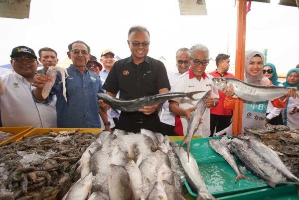 Isham (tengah) bersama Ahmad Badli Shah (dua dari kanan) melihat ikan dijual Pasar Tani Putrajaya pada Jumaat.