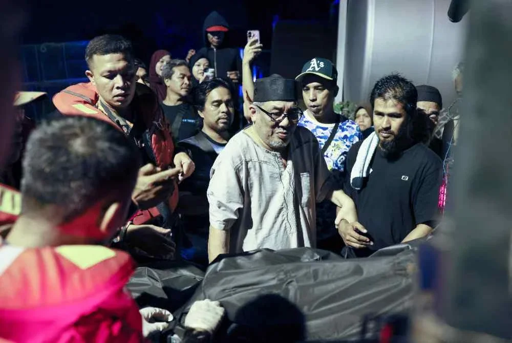 Mohmad Jalil Musa, 69, berada di sisi jenazah anaknya, Ahmad Nasaruddin yang maut selepas bot mencandat sotong yang dinaikinya karam kira-kira sembilan batu nautika dari Kuala Nerus ketika dibawa ke Jeti LKIM Kampung Batin. Foto Bernama