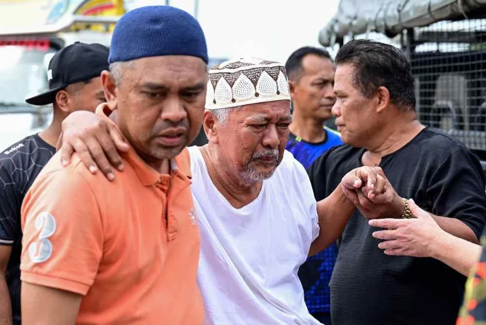 Bapa mangsa, Din Zakaria (tengah) tidak dapat menahan kesedihan selepas anaknya ditemukan selepas terjatuh dari jambatan Sungai Paka di Jalan Jabor-Paka berhampiran Bandar Al Muktafi Billah Shah. Foto Bernama