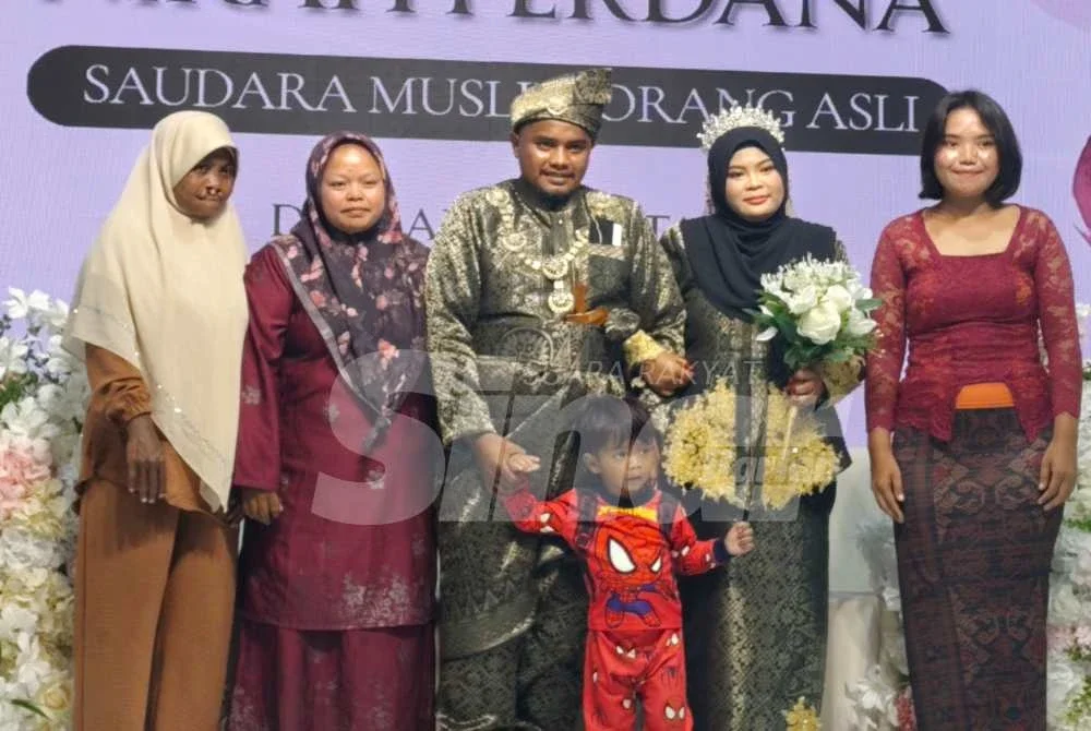 Izzat bersama pasangannya Fara merakam gambar kenangan bersama keluarga pada Program Walimatul Urus dan Nikah Perdana Saudara Muslim Orang Asli Daerah Kuantan di sebuah dewan di Jaya Gading di sini pada Sabtu. Foto Sinar Harian