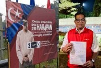 Mohamad Shafwan menunjukkan laporan polis yang dibuat berhubung papan tanda kempennya yang dikoyakkan di bahagian muka.