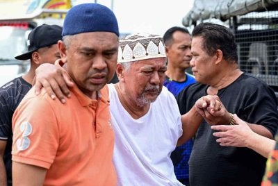 Bapa mangsa, Din Zakaria (tengah) tidak dapat menahan kesedihan selepas anaknya ditemukan selepas terjatuh dari jambatan Sungai Paka di Jalan Jabor-Paka berhampiran Bandar Al Muktafi Billah Shah. Foto Bernama