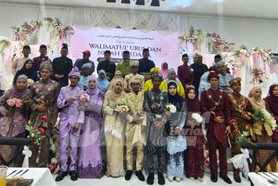 Dr Asmadi (tengah) bersama 13 pasangan pengantin dari mualaf Orang Asli bergambar pada Program Walimatul Urus dan Nikah Perdana Saudara Muslim Orang Asli Daerah Kuantan di sebuah dewan di Jaya Gading di sini pada Sabtu. Foto Sinar Harian