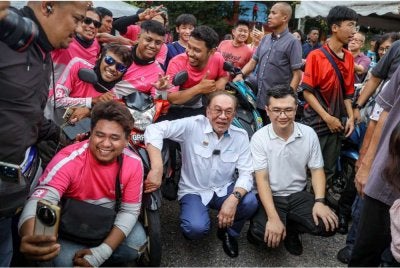 Anwar (tengah) bergambar dengan penghantar makanan Food Panda pada Program Kita Genk Madani Johor di Kulai. Foto Bernama