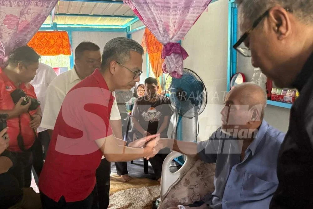 Fahmi (kiri) melawat penduduk di Parit Maimon sempena Ziarah Kasih Kementerian Komunikasi pada Ahad.