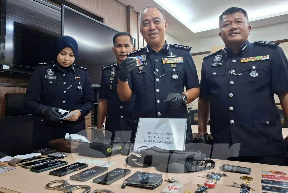 Mohd Alwi (dua dari kanan) menunjukkan kad kuasa polis bantuan dan barangan kes yang dirampas susulan penahanan tiga lelaki di Manjung, Khamis lalu.