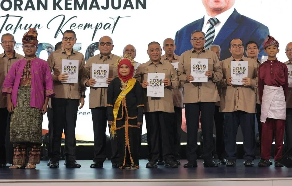 Saarani (depan, tengah) bersama Ahli-ahli Majlis Mesyuarat Kerajaan Negeri menunjukkan buku Laporan Kemajuan Tahun Keempat Perak Sejahtera 2030 yang turut dilancarkan di Pusat Konvensyen Casuarina di Ipoh pada Isnin.