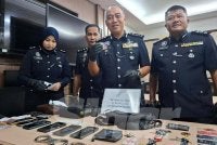 Mohd Alwi (dua dari kanan) menunjukkan kad kuasa polis bantuan dan barangan kes yang dirampas susulan penahanan tiga lelaki di Manjung, Khamis lalu.