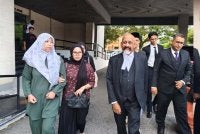 Nurhaswani Afni (kiri) bersama Naran Singh (kanan) sebaik selesai prosiding di Mahkamah Majistret Ipoh pada Isnin bagi pertuduhan melakukan kekerasan jenayah terhadap Sultan Perak, Sultan Nazrin Muizzuddin Shah ketika sambutan Hari Kebangsaan tahun lalu.
