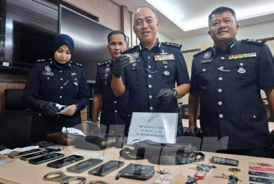 Mohd Alwi (dua dari kanan) menunjukkan kad kuasa polis bantuan dan barangan kes yang dirampas susulan penahanan tiga lelaki di Manjung, Khamis lalu.