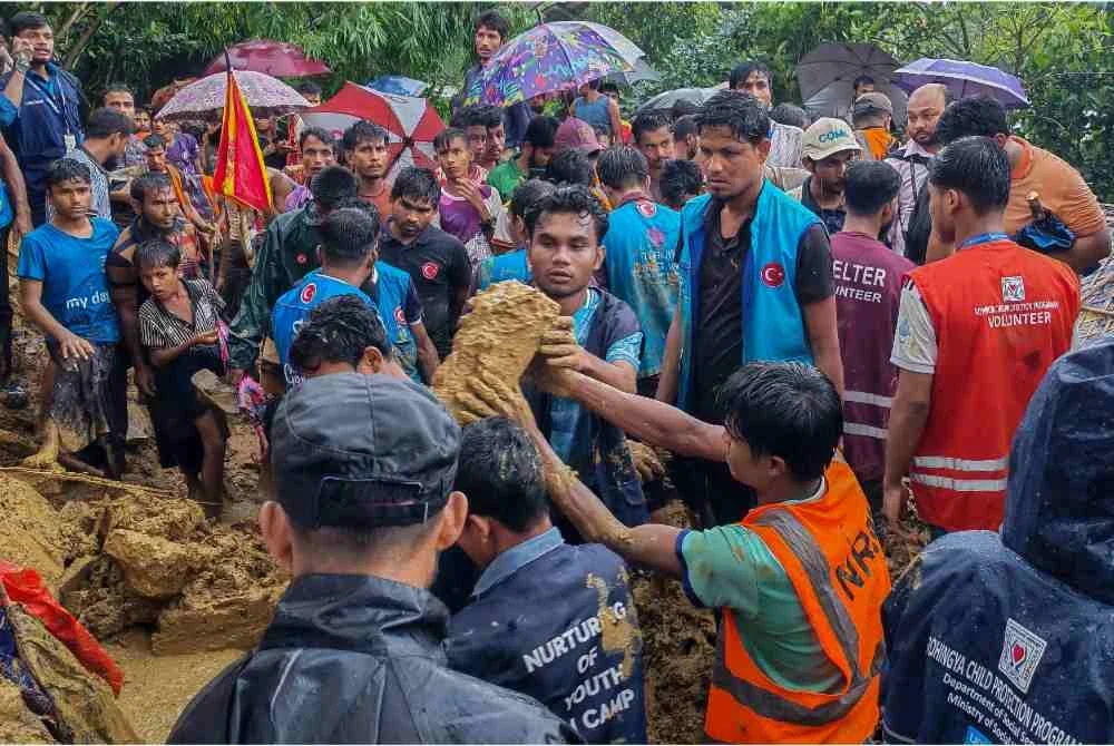 Anggota keselamatan dan sukarelawan membantu mangsa tanah runtuh di kem pelarian Cox Bazar pada Rabu. - FOTO: AFP 