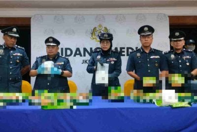 Wan Marini (tengah) menunjukkan bungkusan teh mengandungi dadah yang dicampakkan ke dalam laut di perairan Pulau Telur. 