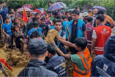 Anggota keselamatan dan sukarelawan membantu mangsa tanah runtuh di kem pelarian Cox Bazar pada Rabu. - FOTO: AFP 