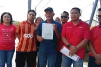 Hairu Nasir (tengah) menunjukkan laporan polis yang dibuat di Balai Polis Simpang Renggam pada Khamis.