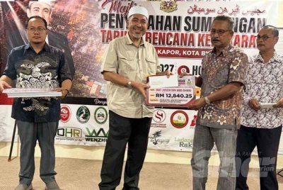 Mat Jusoh (dua dari kanan) yang menerima wang sumbangan disampaikan Dr Izani. Foto Adila Sharinni Wahid
