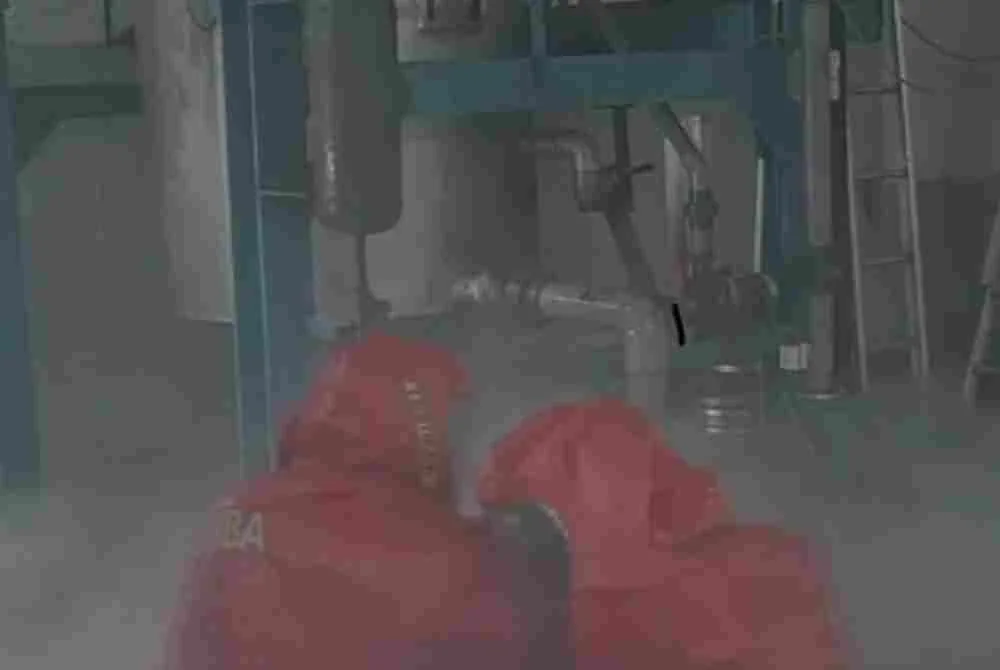 Dua anggota Pasukan Khas Bahan Kimia Berbahaya (Hazmat) dengan kelengkapan perlindungan diri (PPE) lengkap telah memasuki lokasi bagi menutup injap silinder terbabit. Foto: JBPM Perak