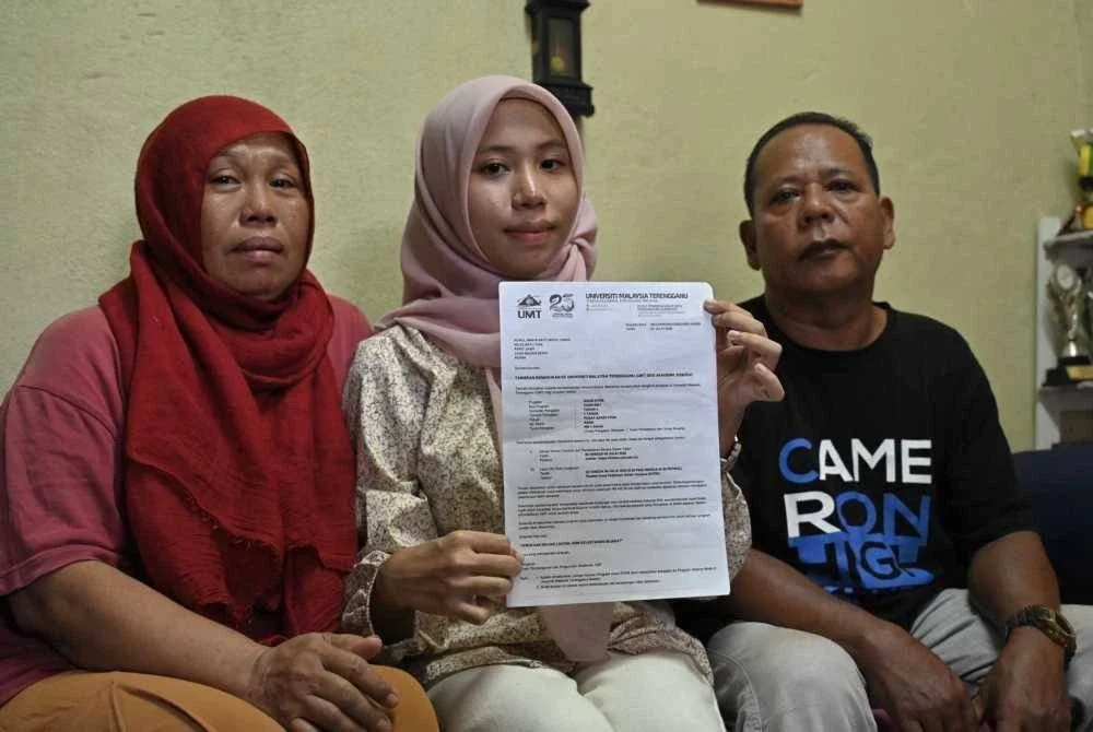 Nurul Amira (tengah) bersama kedua ibu bapanya menunjukkan surat tawaran kemasukan ke UMT ketika ditemui pada Jumaat.