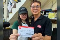 Lynn (kiri) bersama bapanya, Sek Hua menunjukkan tiket penerbangannya dari Chengdu ke Kuala Lumpur untuk menunaikan tanggungjawab sebagai pengundi pada PRN Johor Ke-16. Foto: Bernama