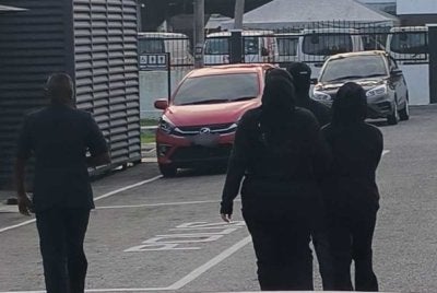 Remaja memakai baju berhud hitam dan berpelitup muka (kanan) dibawa ke Mahkamah Telok Datok pada jam 8.32 pagi Jumaat.