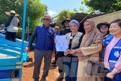 Kheng Luan (tiga,kiri) bersama Wan Kasma (dua,kanan) menunjukkan plan rumah rakit sumbangan KDRN di Rantau Panjang pada Jumaat. Foto:HAZELEN LIANA KAMARUDIN