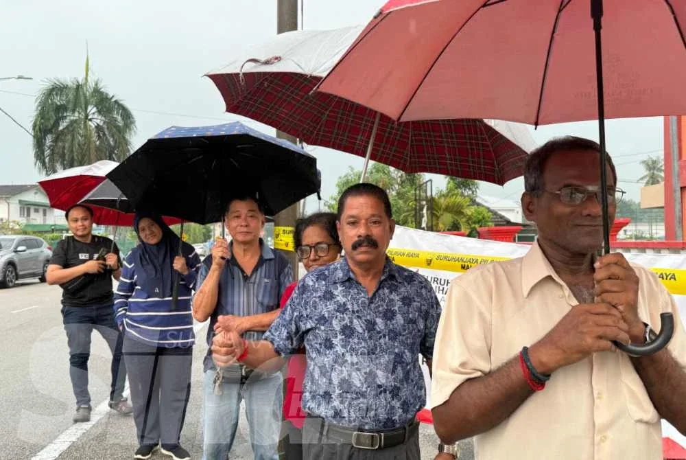 Gunasekaran (depan) antara pengundi awal beratur di SMK Muar bagi membuang undi.