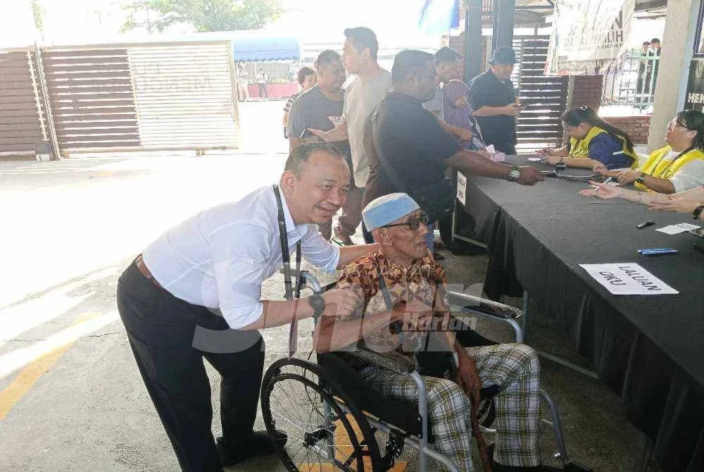 Maszlee bergambar dengan seorang warga emas di pusat mengundi di SJKC Tuan Poon, Simpang Renggam.