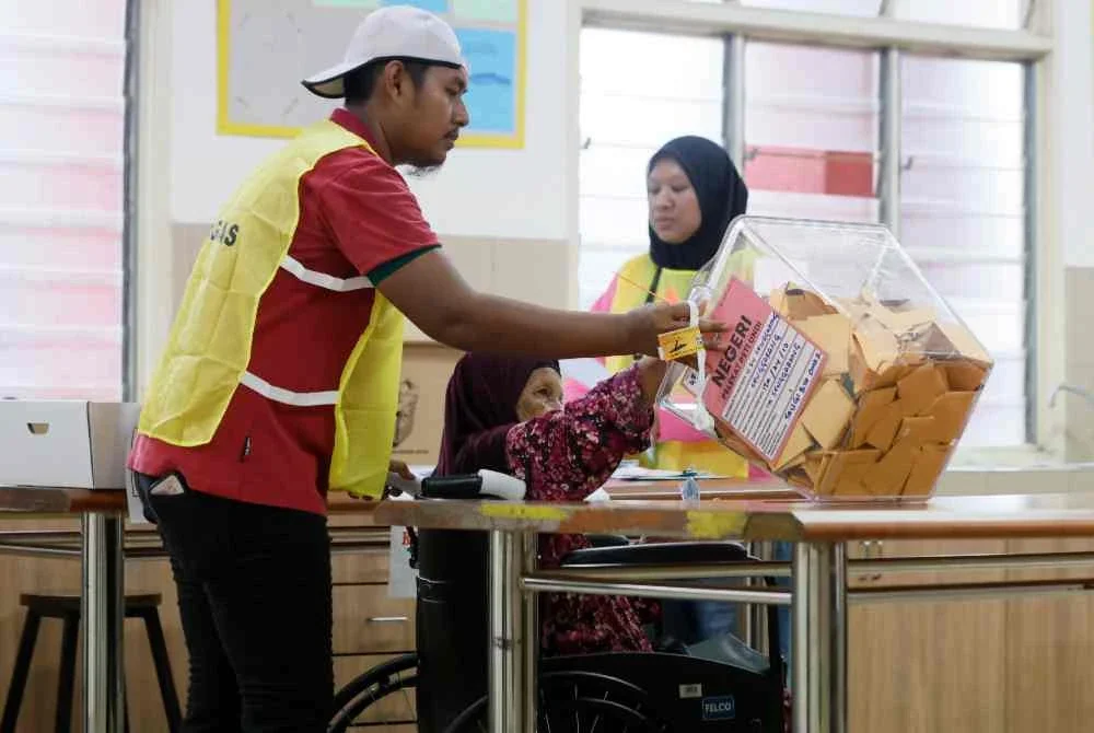 Petugas SPR membantu warga emas, Siti Anipah Kasbolah, 78, mengundi ketika melaksanakan tanggungjawab mengundi bagi kerusi Dewan Undangan Negeri (DUN) Senggarang pada PRN Johor ke-16 di Pusat Menggundi Sekolah Kebangsaan Senggarang pada Sabtu. Foto Bernama