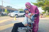 Lia Isabella yang merupakan pesakit Cerebral palsy diiringi penjaganya, Salihaton Awang selesai menunaikan tanggungjawab sebagai pengundi di Pusat Mengundi SJKC Kulai Besar, Kulai pada Sabtu.