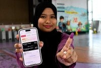 Aina Nazirah menunjukkan jari berdakwat selepas mengundi pada PRN Johor ke-16 di Sekolah Jenis Kebangsaan Cina Tongkang pada Sabtu. Foto: Bernama
