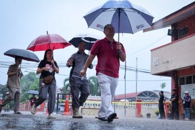 Hujan yang turun sejak awal pagi tadi tidak membataskan pergerakan pengundi untuk hadir bagi menunaikan tanggungjawab mereka. Foto Bernama