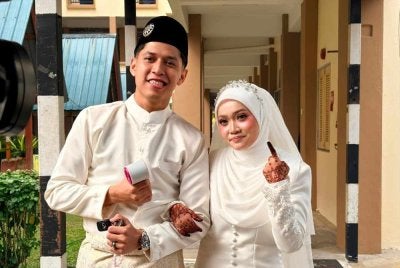 Fifi Nur Khairin ditemani suaminya, Muhammad Arif Fahmi di pusat mengundi di SK LKTP Sungai Sayong, Kota Tinggi selepas selesai majlis akad nikah.