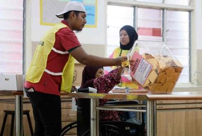 Petugas SPR membantu warga emas, Siti Anipah Kasbolah, 78, mengundi ketika melaksanakan tanggungjawab mengundi bagi kerusi Dewan Undangan Negeri (DUN) Senggarang pada PRN Johor ke-16 di Pusat Menggundi Sekolah Kebangsaan Senggarang pada Sabtu. Foto Bernama