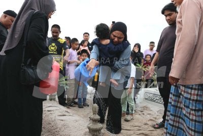 Farah Aqilah menyiram air mawar di pusara suaminya, Allahyarham Muhammad Hafiz Al Hakim yang selamat dikebumikan di Tanah Perkuburan Islam Kampung Limbong, Paka di Dungun pada Sabtu.