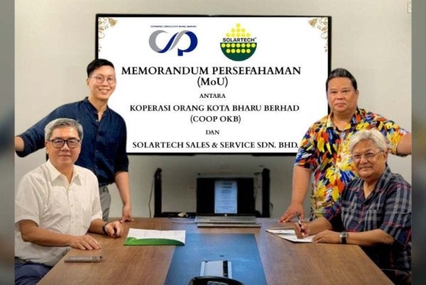Nik Izani (duduk kanan) dan Roy Chok (duduk kiri) ketika sesi menandatangi MoU antara COOP OKB dan Solartech Sales & Service Sdn Bhd pada Isnin.