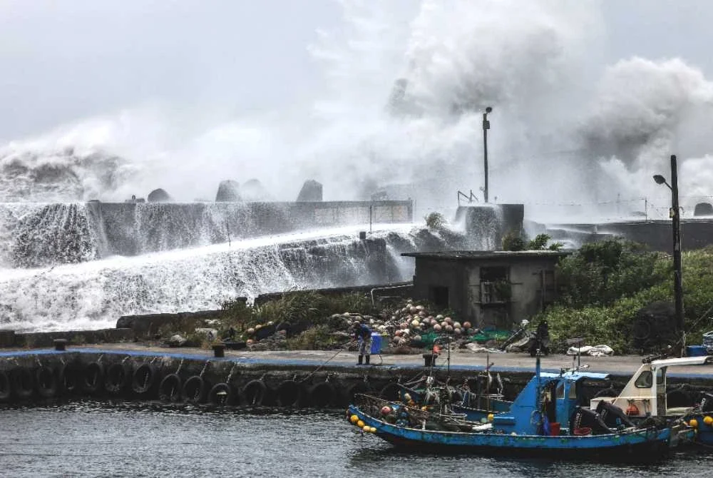 Seorang nelayan mengendalikan tali berhampiran sebuah bot nelayan ketika ombak ganas menghempas benteng di Yilan, timur laut Taiwan. Foto AFP