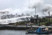 Seorang nelayan mengendalikan tali berhampiran sebuah bot nelayan ketika ombak ganas menghempas benteng di Yilan, timur laut Taiwan. Foto AFP