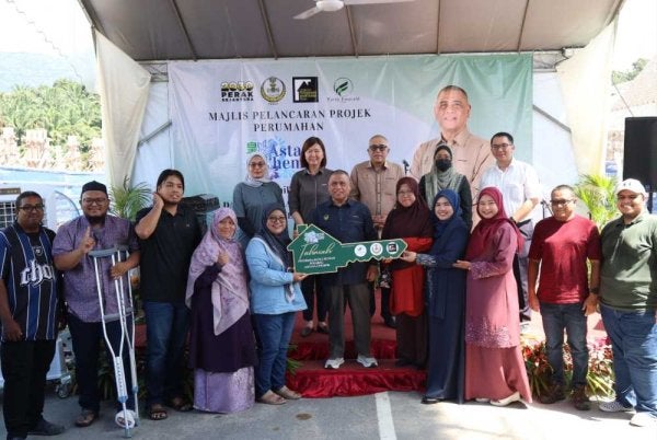 Saarani (tengah) menyerahkan replika kunci kepada penerima kunci sebagai simbolik Perasmian Projek Perumahan Perakku Astana Chemor pada Ahad.