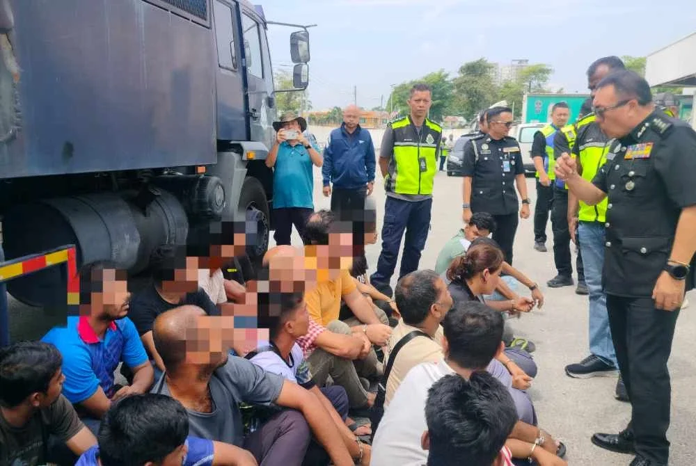 James (kanan) bertanyakan sesuatu kepada warga asing yang ditahan dalam Operasi Bersepadu di sekitar Ipoh pada Isnin.